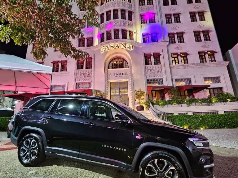 SUV preto Jeep Commander estacionado à noite em frente ao Hotel Fasano iluminado, transfer executivo